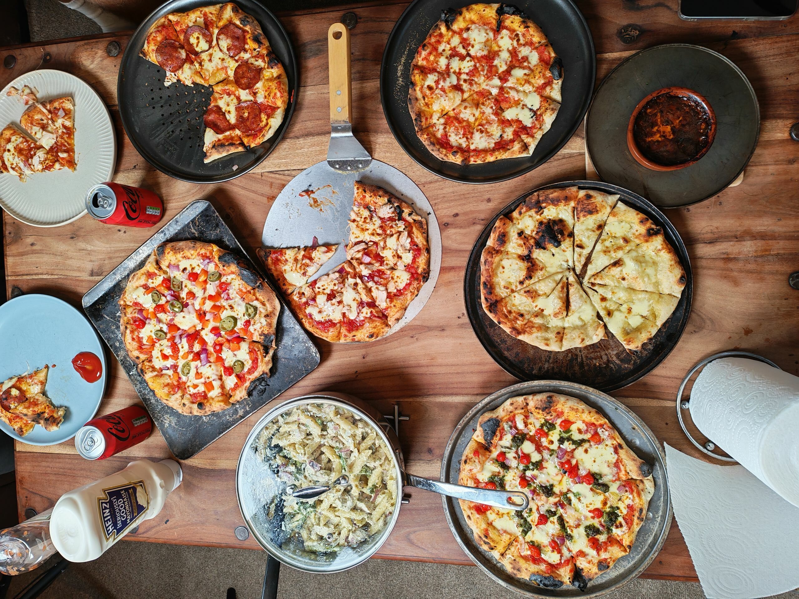 Top view of a table filled with various pizzas, pasta, and beverages, perfect for a feast.
